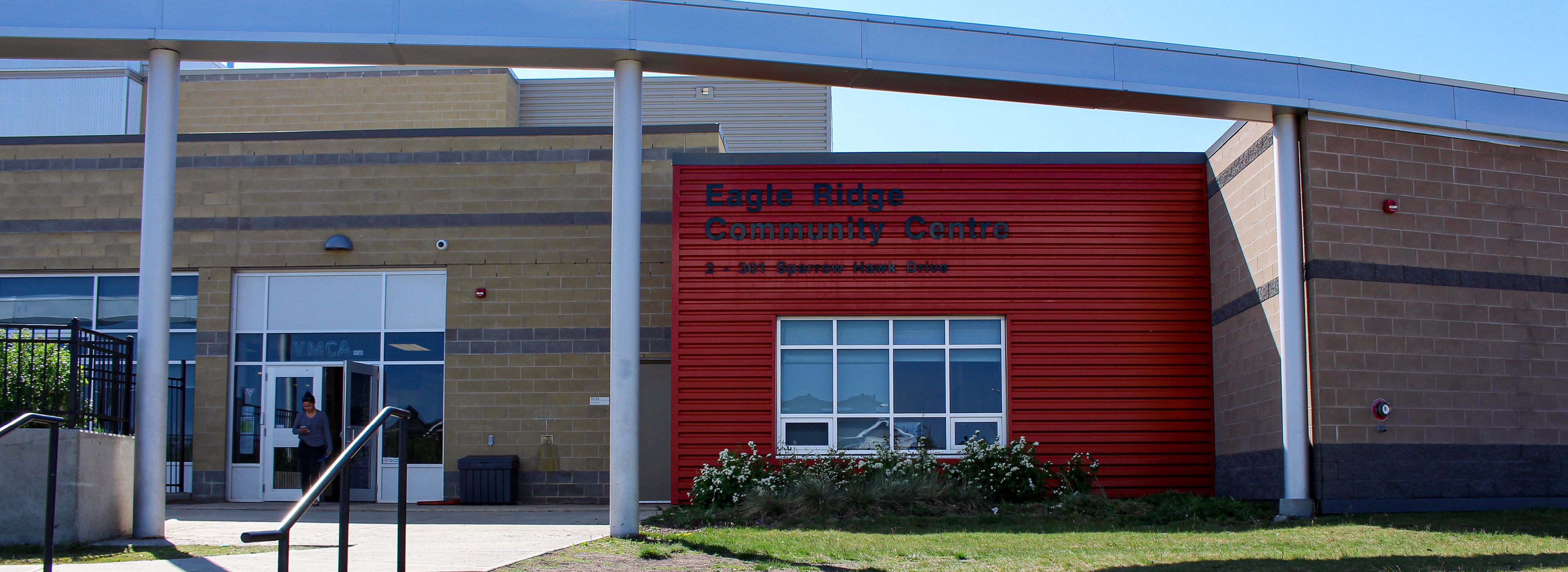 A modern brick building features a stainless steel arch that goes over the main walkway.