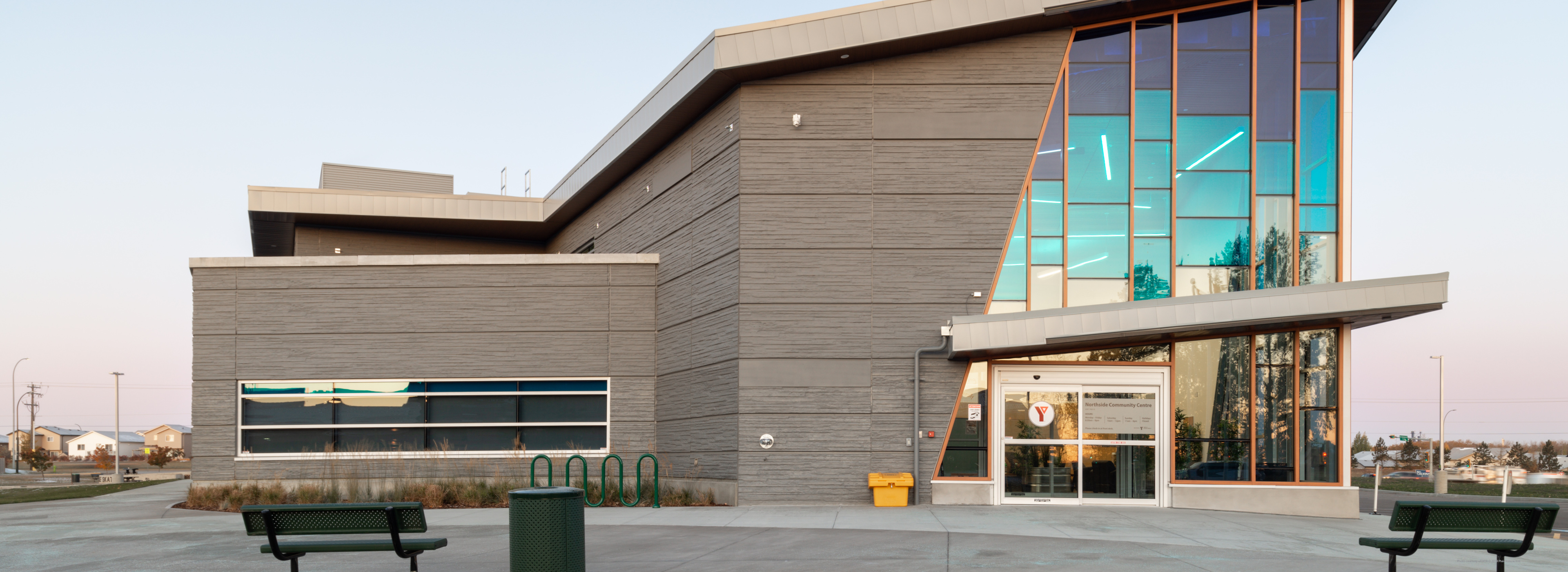 A modern building features a large glass entrance way with a gradient blue tint.