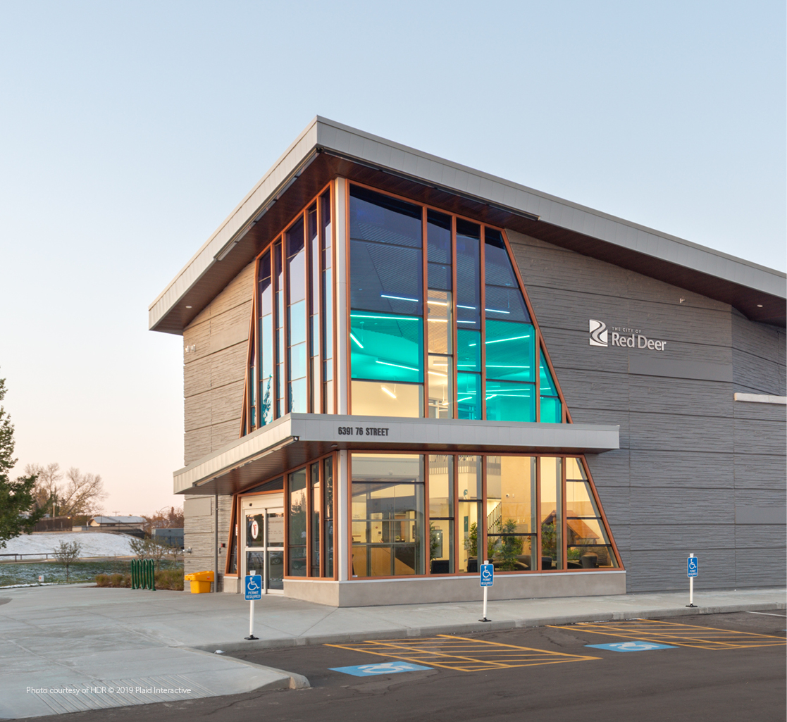A modern building features a large glass entrance way with a gradient blue tint.