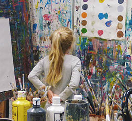 A young girl stairs at a wall of paint.