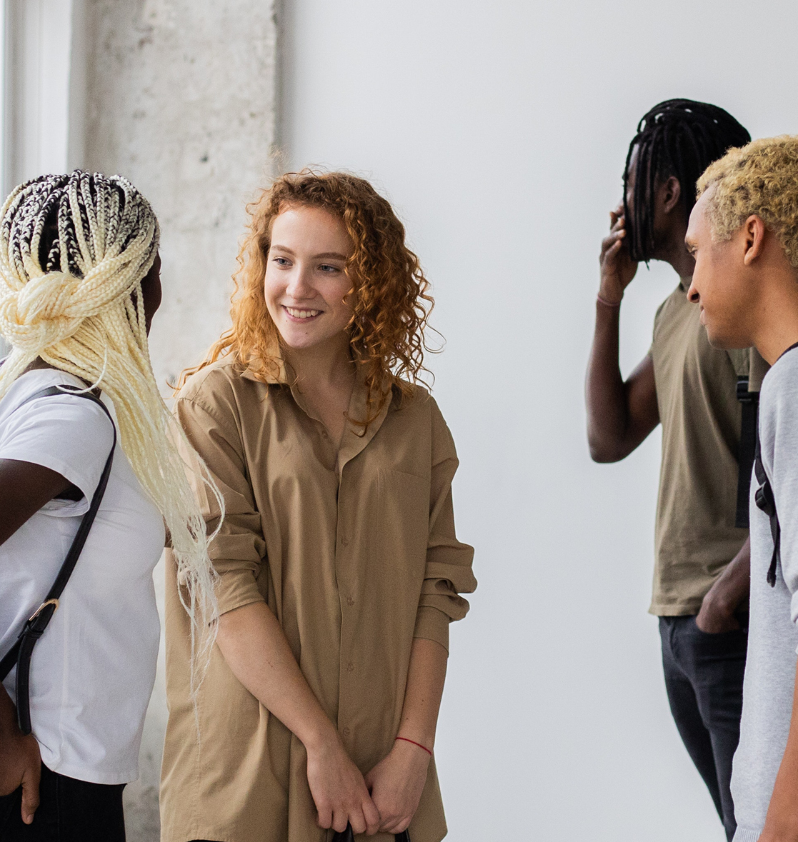 A group of teens gather in a circle and laugh while inside a building