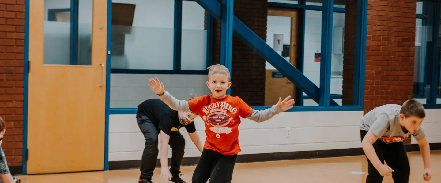 A young boy runs inside a studio space with his arms in the air.