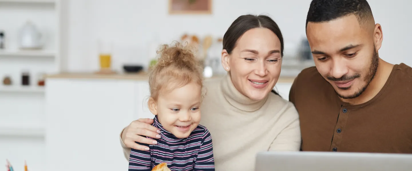 Portrait of smiling mixed race family using laptop together while using a computer.