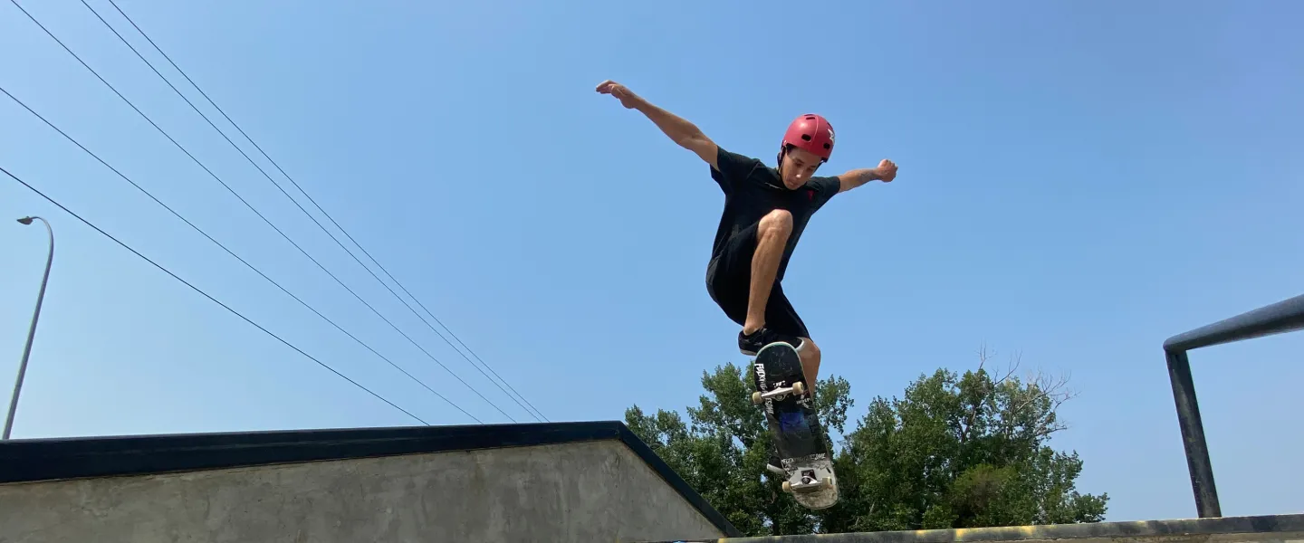 A young man rides a skateboard over an outdoor staircase and winds up for a trick.