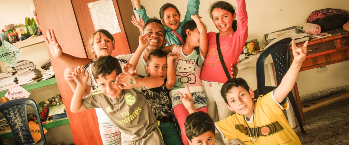 A group of youth stand together with their arms up