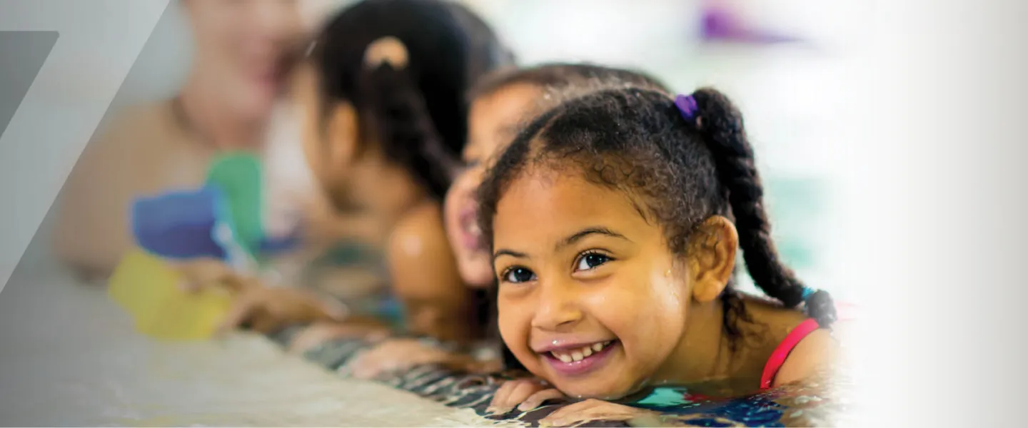 swimming camps Edmonton web banner - a little girl in the swimming pool smiling during a swimming lesson