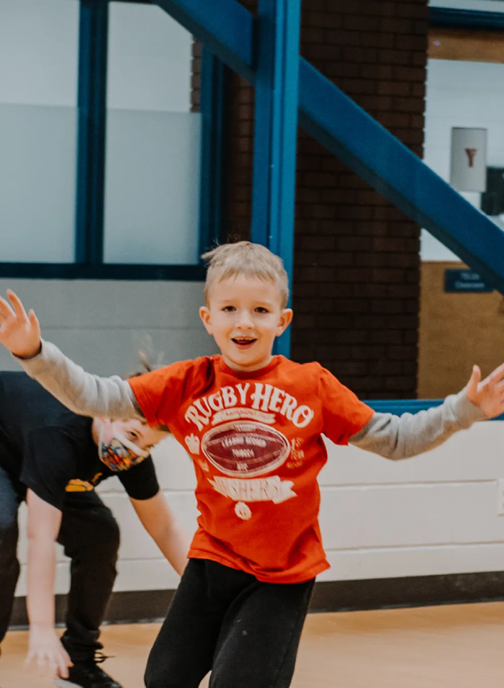 A young boy runs inside a studio space with his arms in the air.