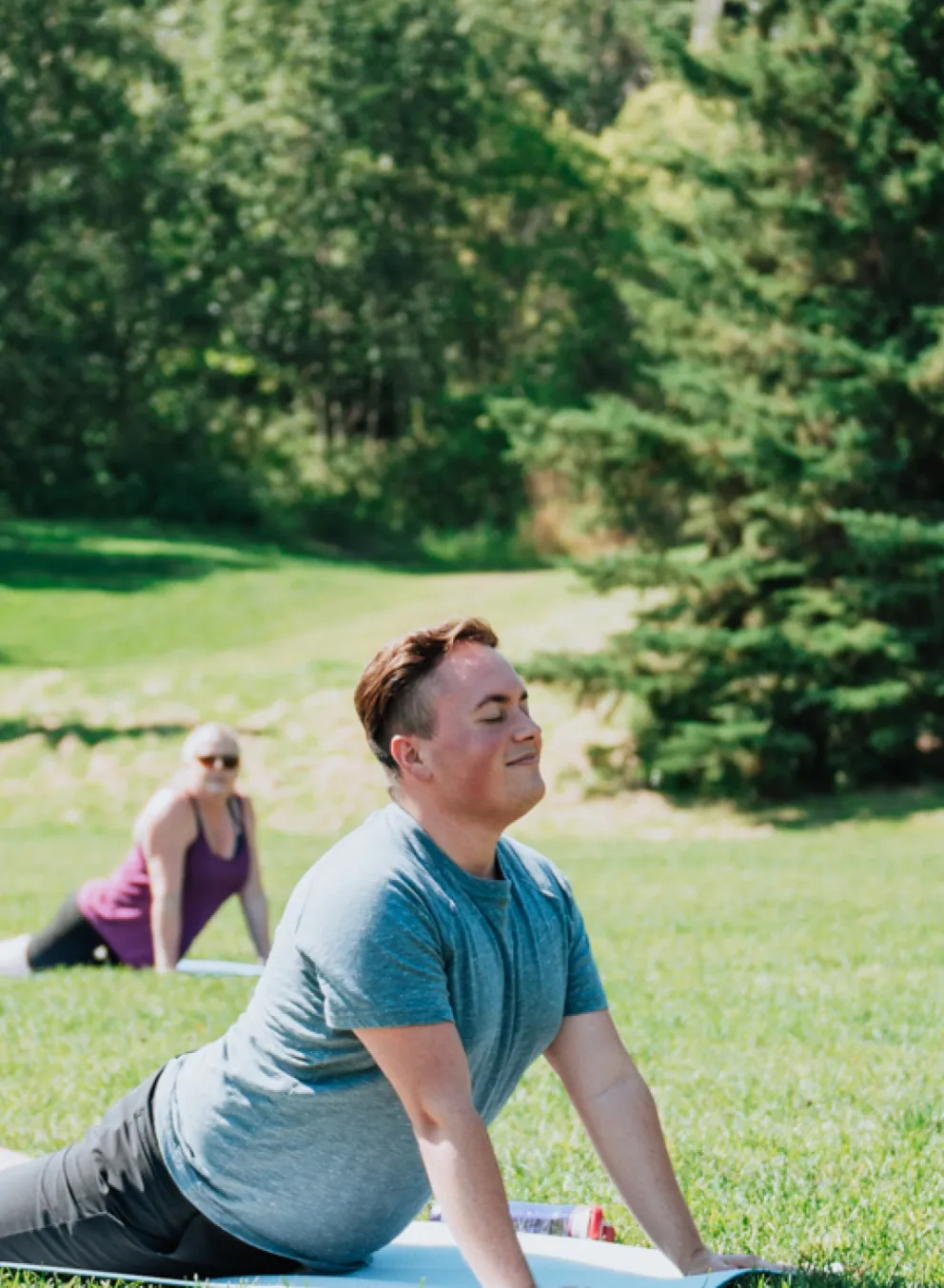 A diverse group of young adults participate in a yoga class outdoors.