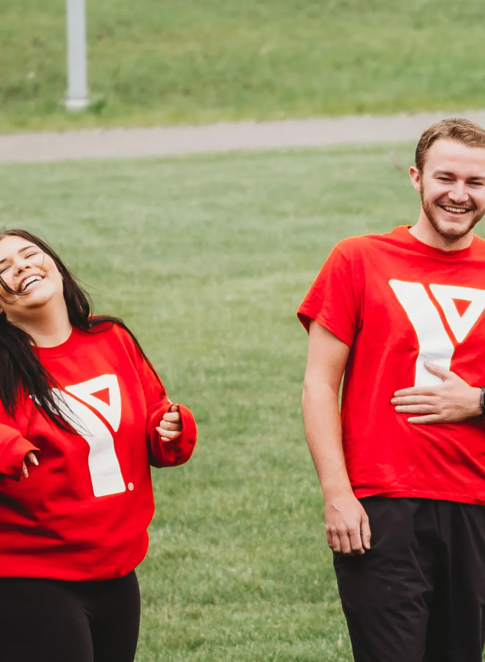 A group of YMCA day camp staff laugh together outdoors.