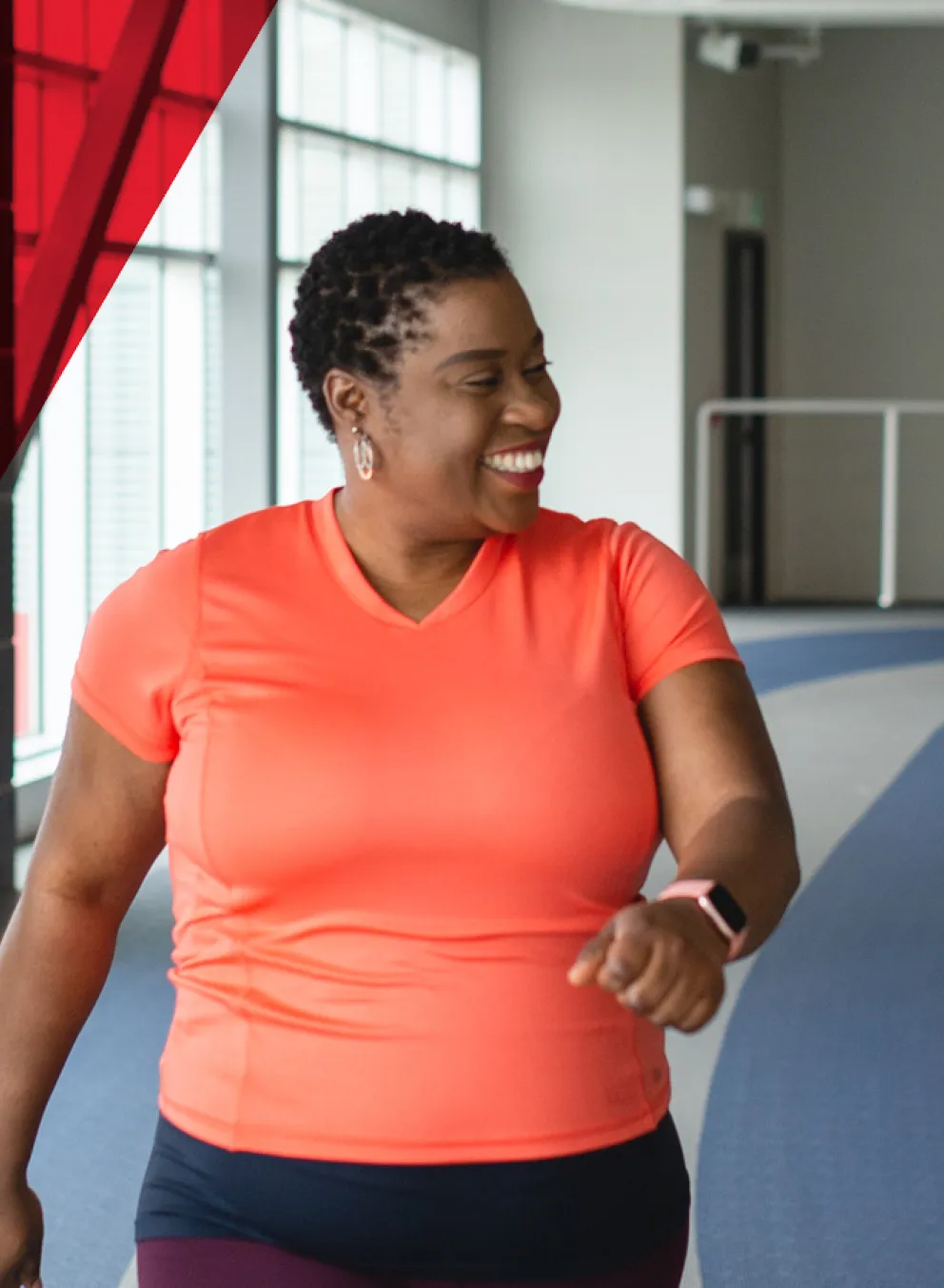 three ladies are walking and passing a smile at each other while walking on an indoor walking track at the Y