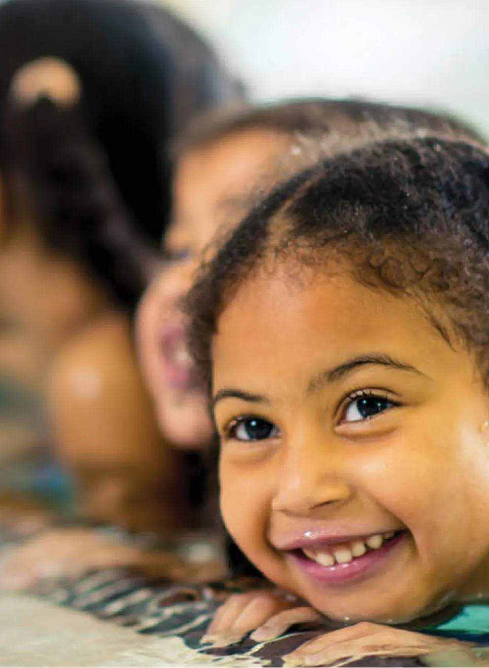 swimming camps Edmonton web banner - a little girl in the swimming pool smiling during a swimming lesson