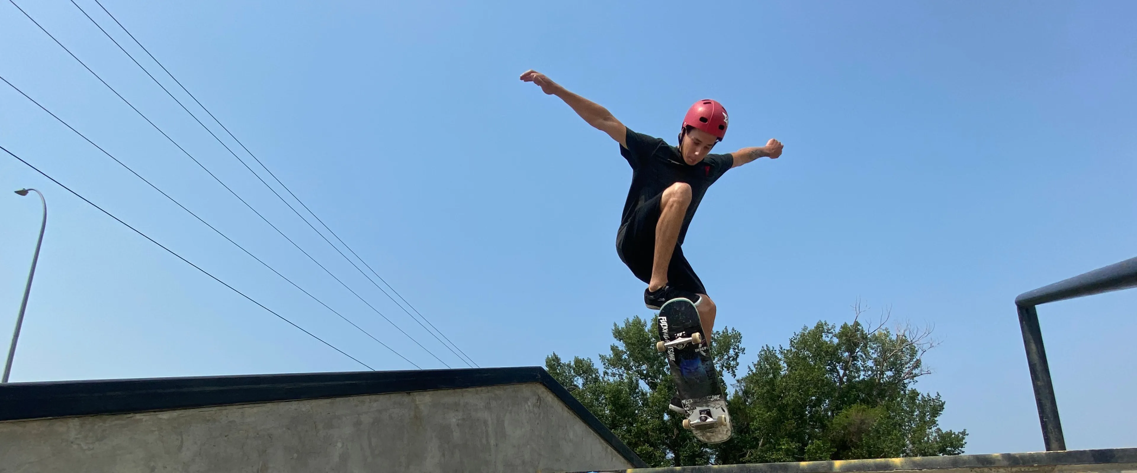 A young man rides a skateboard over an outdoor staircase and winds up for a trick.