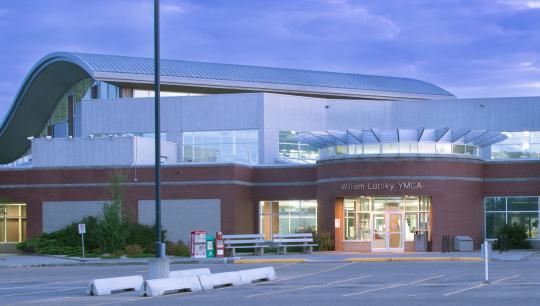 A brick building with a wavy roof seen at dusk.