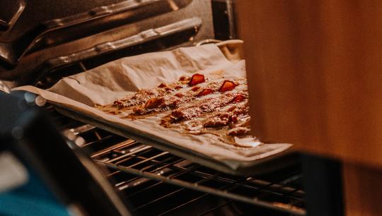 A baking sheet with bacon glistens in the over light.