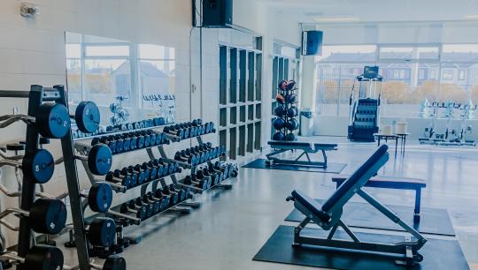 A fitness studio featuring dumbells, adjustable benches and more fitness equiptment.