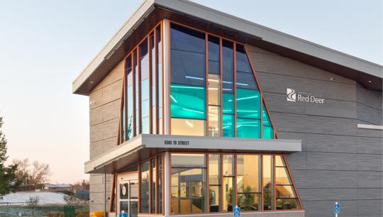 A modern building features a large glass entrance way with a gradient blue tint.