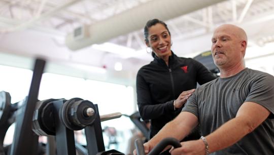 A man exercising with direction from a woman trainer