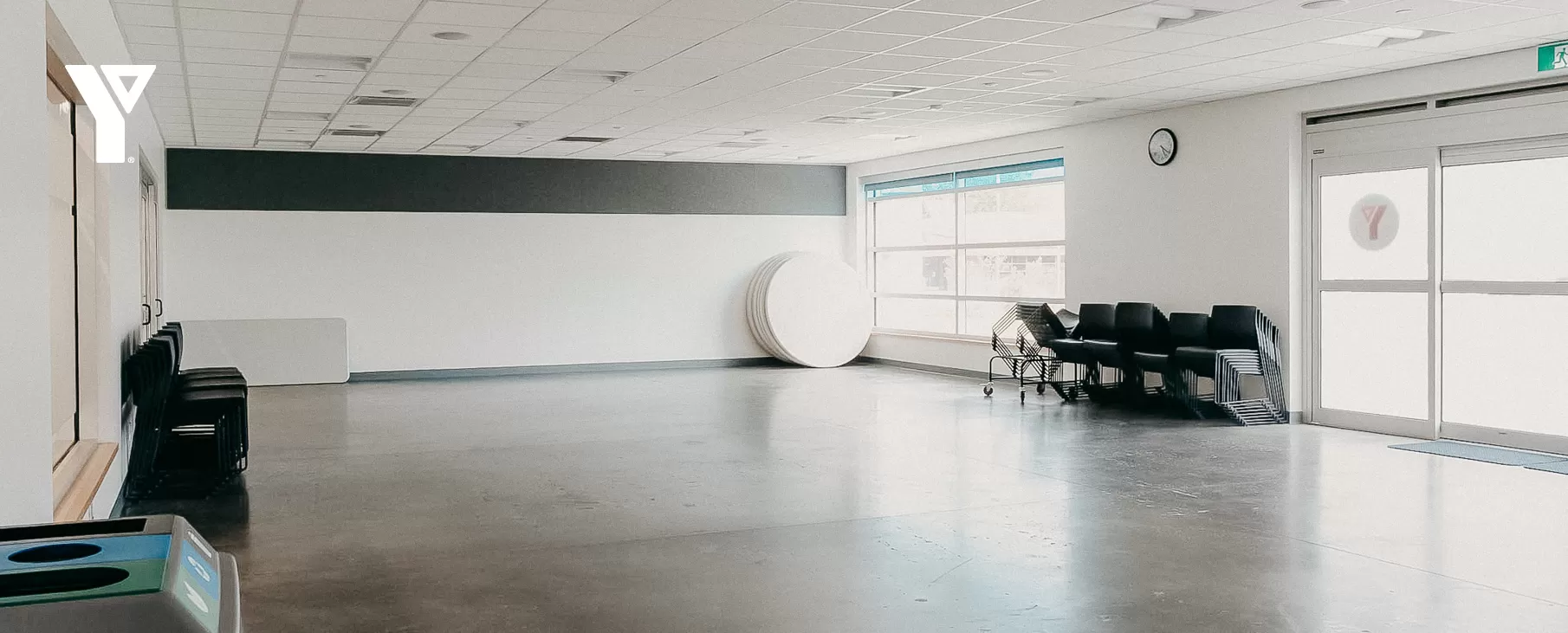 Sun fills a large room seen with tables and chairs neatly placed against a far wall.