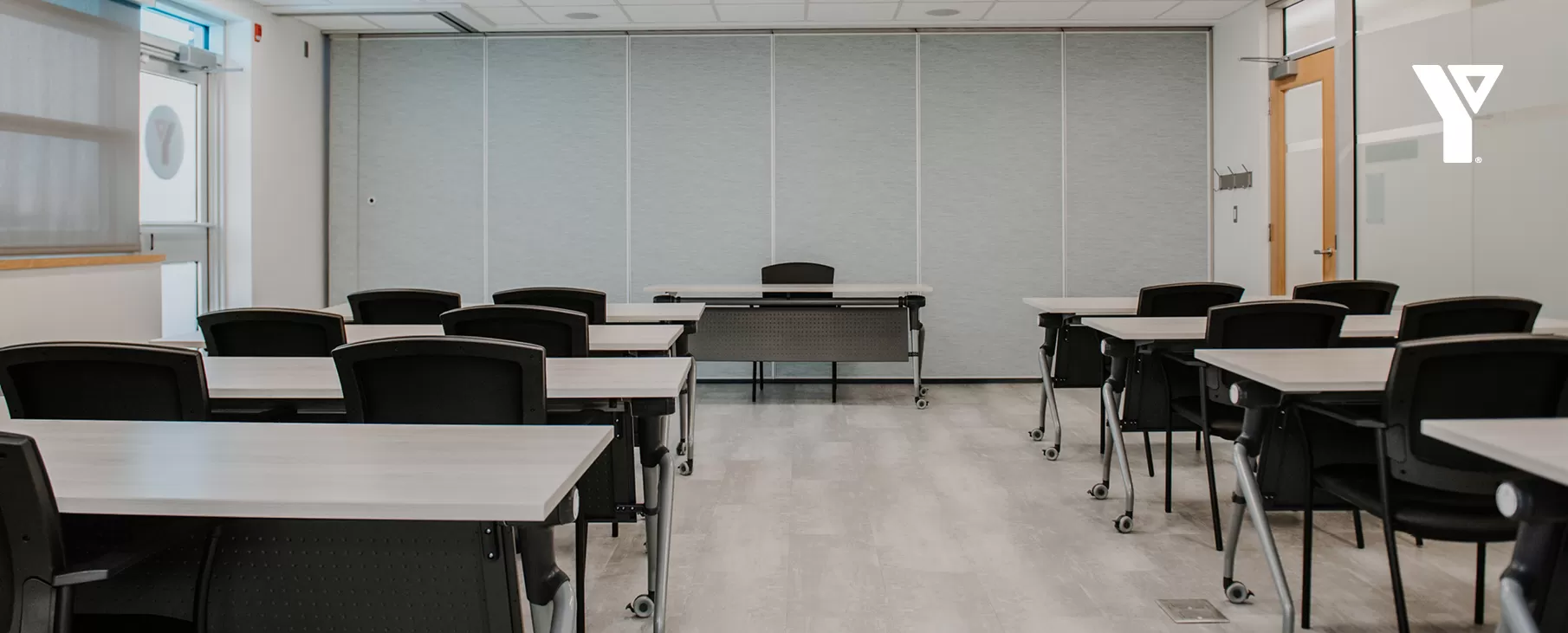 A modern multipurpose room with tables and chairs set up in a teaching setting.