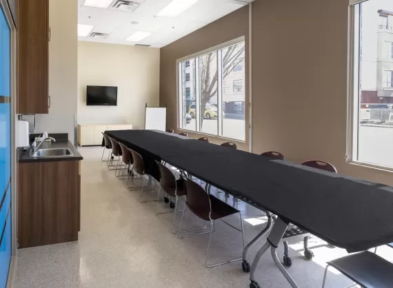 long desk with chairs, a window, tv, sink