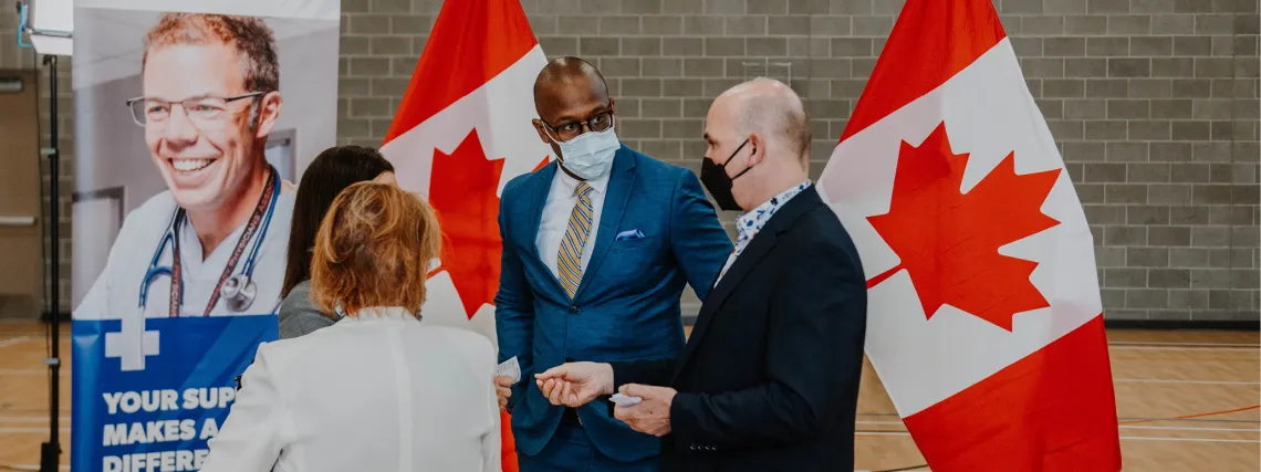 A group of well-dressed men and women stand together after a media event.