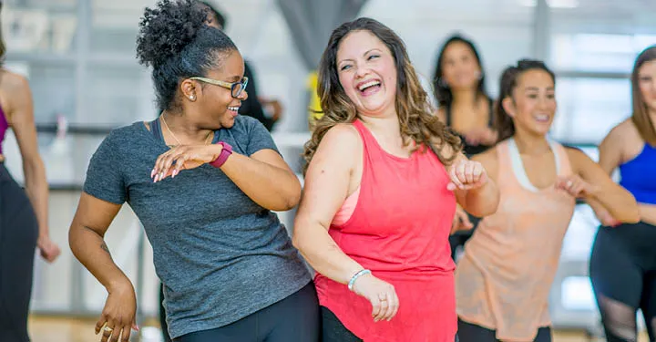 A group of diverse women dance during a group fitness class.